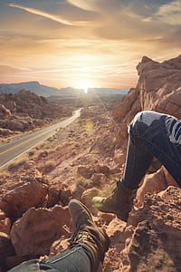 person on top of cliff near road thumbnail