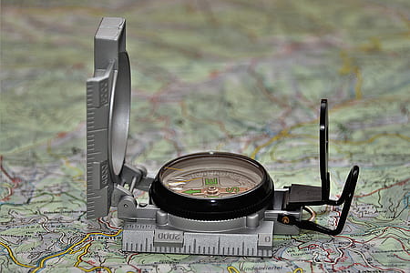 round black and gray analog compass on green map thumbnail