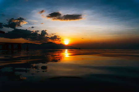 photography of sea across hill at sunset thumbnail