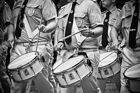 grayscale photo of men marching with drums thumbnail