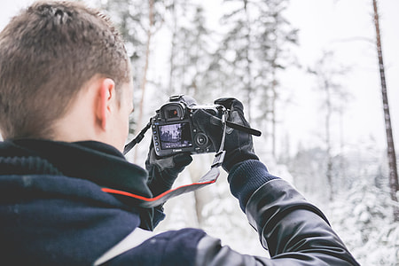 Photographer in Snowy Forest Taking Winter Photos thumbnail