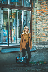 woman holding black leather bag standing in front of window thumbnail