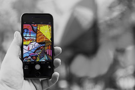 person holding iPhone displaying graffiti painting thumbnail