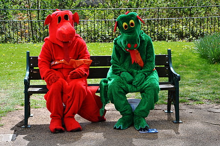 two person wearing red and green dinosaur mascots while sitting on black wooden bench during daytime thumbnail