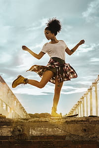 woman standing on asphalt road while posing under cloudy sky thumbnail
