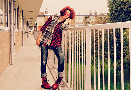 woman wearing black and white long-sleeved shirt and distressed blue jeans leaning on white rails thumbnail
