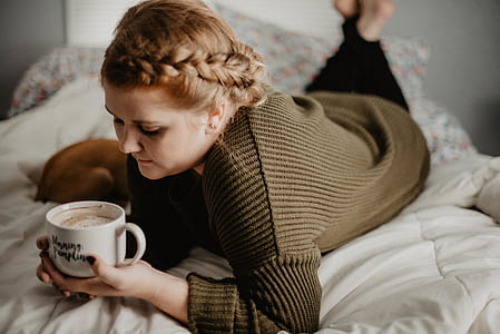woman holding ceramic mug while laying on bd thumbnail