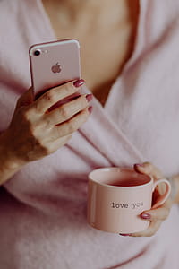 A woman in a pink sweater holds a pink iPhone and a pink cup in her hands thumbnail
