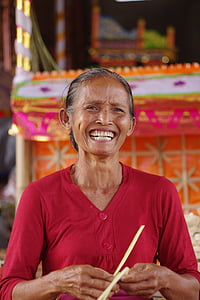 woman smiling while holding yellow string on front of orange and yellow altar thumbnail