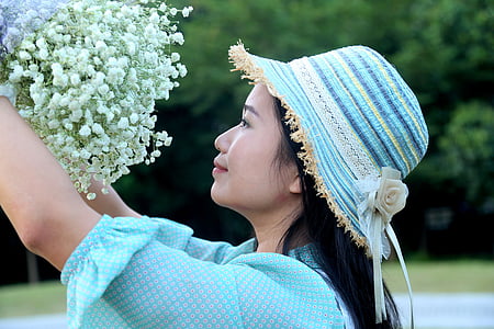 woman wearing teal top and striped hat holding white cluster flowers thumbnail