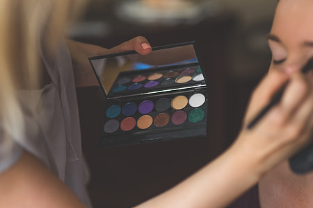 woman in white top holding make-up palette thumbnail