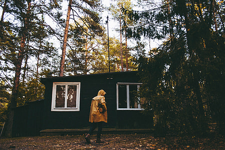 man standing in front of house surrounded by trees thumbnail