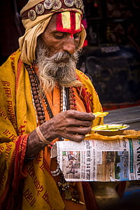 man in yellow and red traditional dress and brown beaded necklace thumbnail