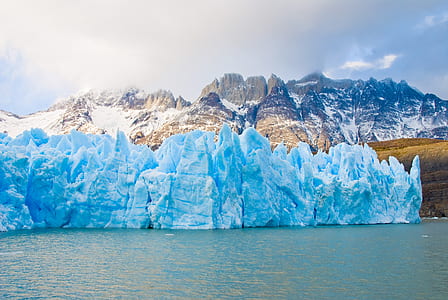 glaciers on the food of mountain range near body of water thumbnail