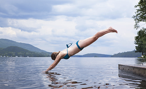 woman diving on body of water during daytime thumbnail