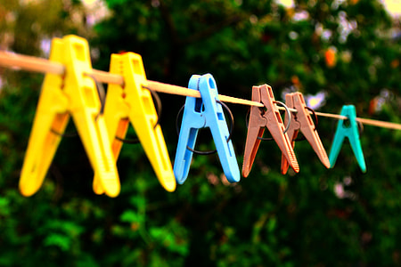 focus photo of six plastic clothes pegs hanging on a yellow cable thumbnail
