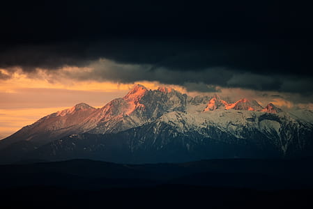 mountain covered with snow under cloudy sky thumbnail