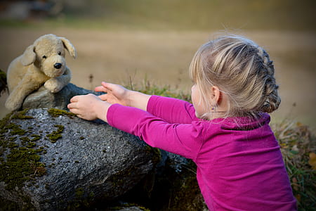girl wearing pink long-sleeved top holding brown dog plush toy thumbnail