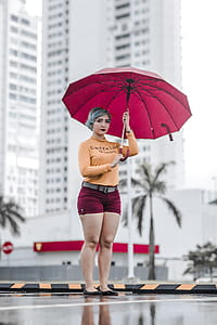 Photo of Standing Woman Holding an Umbrella with a White High-rise Building in the Background thumbnail