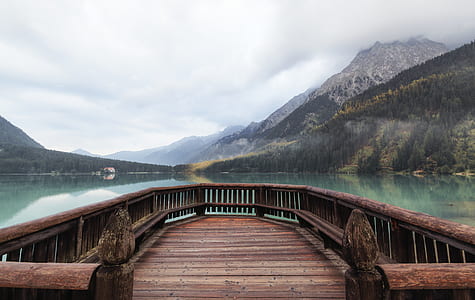brown dock near lake and mountain under white cloud blue skies thumbnail
