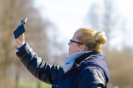 selective focus photography of woman taking selfie near forest thumbnail