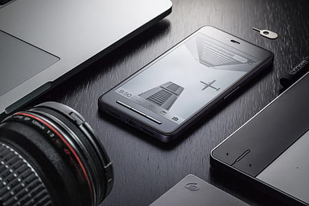 grayscale photography of black Android smartphone between laptop and camera lens thumbnail