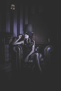 woman holding cigarette while siting on chair thumbnail
