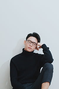 man sitting near white wall thumbnail