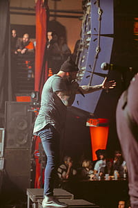 man standing on stage holding microphone thumbnail
