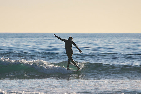 silhouette of person surfing on body of water during daytime thumbnail