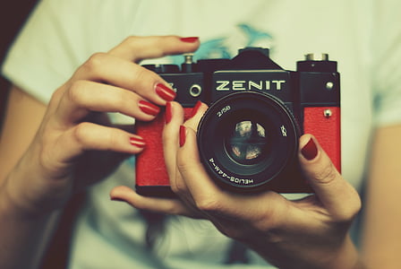 person holding red and black Zenit SLR camera thumbnail