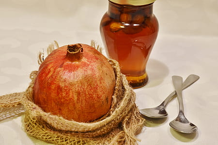 promegranate fruit beside amber glass bottle and two gray teaspoons thumbnail