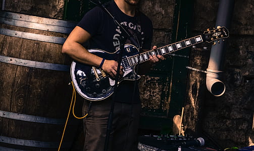 man playing guitar standing near barrel thumbnail