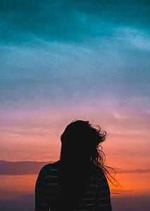 silhouette of woman near seashore during sunset thumbnail