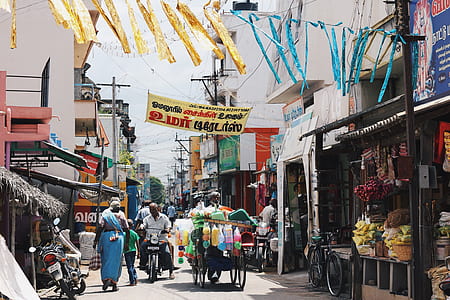man riding on black motorcycle near street food stalls near assorted-color concrete buildings thumbnail