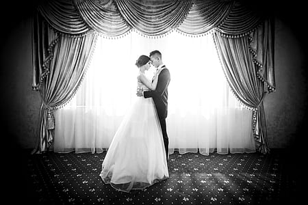grayscale photo of man and woman standing near curtain thumbnail