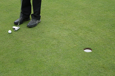 man standing beside golf hole thumbnail