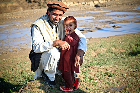man sitting near a boy wearing red long-sleeved shirt holing his mouth thumbnail