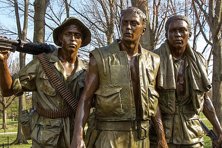 three military statues behind brown bare trees at daytime thumbnail