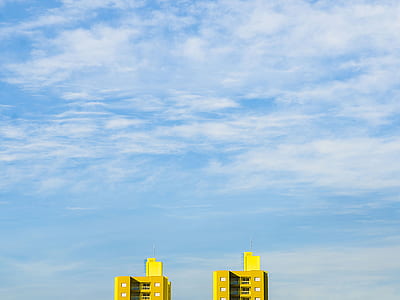 two yellow concrete buildings under white cloudy sky at daytime thumbnail
