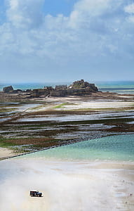 aerial view of vehicle park near castle by the beach thumbnail