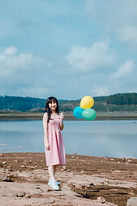 Woman in Pink Dress Holding Balloons thumbnail