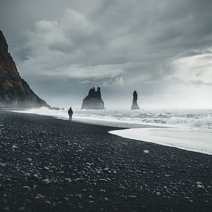 man standing on black beach thumbnail