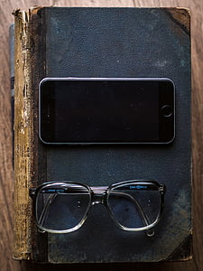 turned off space gray iPhone 6 beside eyeglasses on top of black books on table thumbnail