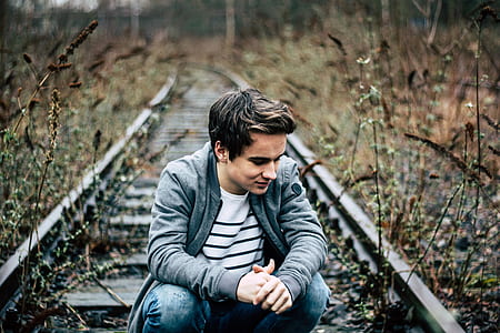 man sitting on gray steel train rail thumbnail