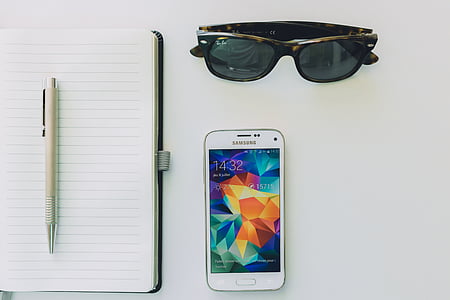 white Samsung Android smartphone near white lined paper with white click pen on top thumbnail