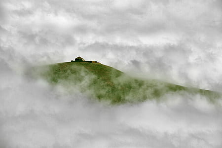 landscape photography of hill under foggy sky thumbnail