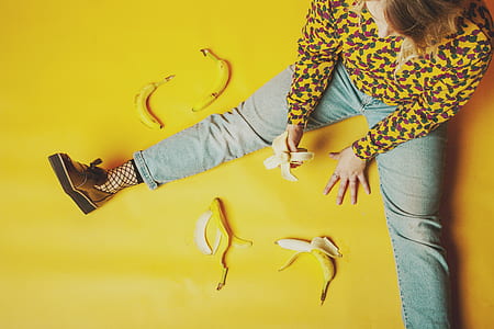 person sitting on yellow surface holding peeled banana thumbnail