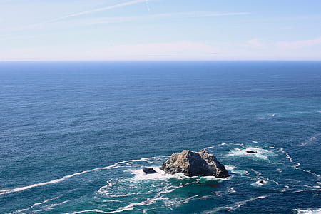grey rock in middle of ocean thumbnail