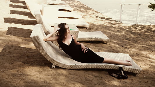 woman in black spaghetti strap dress on beige beach lounge chair thumbnail